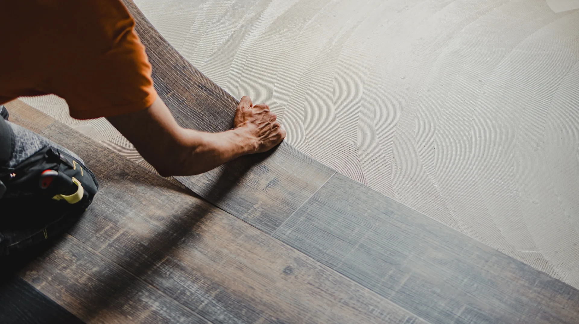 Tradesperson installing dark vinyl plank flooring.